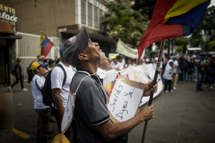 Un hombre sostiene un letrero durante una manifestación en conmemoración del Día Internacional del Trabajo este miércoles, en Caracas (Venezuela). Sindicatos y trabajadores de Venezuela salen a las calles a protestar para exigir un incremento de sus salarios y mejoras en los beneficios laborales. EFE/ Miguel Gutiérrez