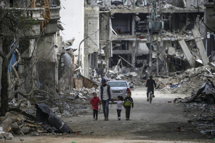 Una familia palestina pasa junto a casas destruidas durante una operación militar israelí en el campo de refugiados de Al Bureije, al sur de la Franja de Gaza, el 13 de febrero de 2024. EFE/EPA/MOHAMMED SABLE
