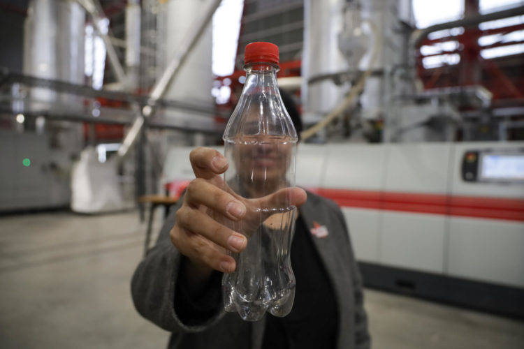 Una mujer sostiene una botella de Coca-Cola vacía durante la inauguración de la primera planta de reciclaje de botellas del sistema Coca Cola ?Re-ciclaren la comuna de Lampa, Santiago (Chile). EFE/ Ailen Díaz