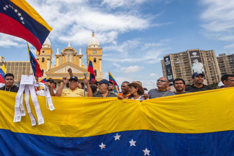 Fotografía del 28 de agosto de 2024 en donde se ven manifestantes que sostienen banderas durante una protesta convocada por María Corina Machado, frente a la Basílica de nuestra señora de Chiquinquirá en Maracaibo (Venezuela). EFE/ Henry Chirinos