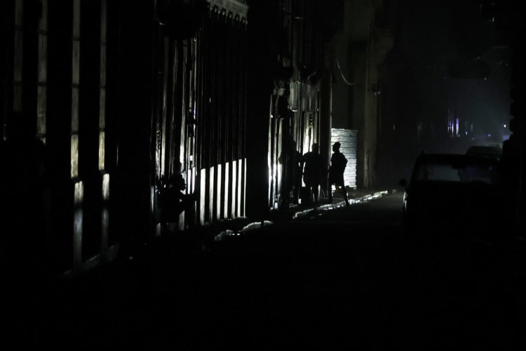 Personas caminan por una calle durante un apagón este viernes, en La Habana, (Cuba). Cuando de verdad se sufre el apagón es de noche. Cuando las casas quedan totalmente a oscuras, las cocinas eléctricas no sirven para preparar la cena, los ventiladores inertes no espantan el calor caribeño y solo las luces de un carro o un celular rompen el negro más rotundo. EFE/ Ernesto Mastrascusa