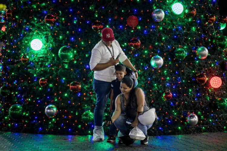 Personas se toman una fotografía junto a un árbol navideño este lunes, en Caracas (Venezuela). EFE/ Miguel Gutiérrez