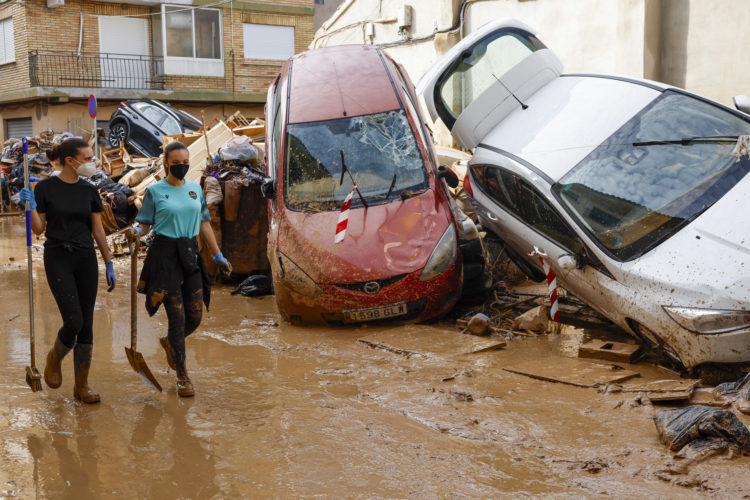 Los vecinos limpian las calles junto a varios coches apilados en Catarroja, Valencia este martes, una de las localidades más afectados por las inundaciones. EFE/ Chema Moya