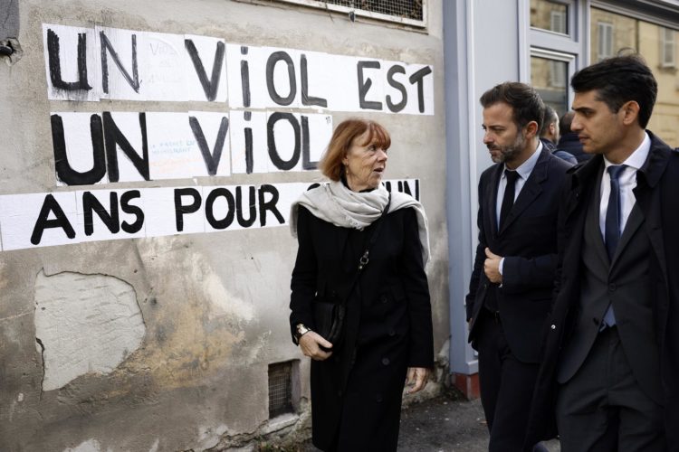 Gisele Pelicot (I), acompañada por sus abogados Stephane Babonneau (D) y Antoine Camus (C), pasa junto a un mensaje en la pared que dice 'La violación es una violación' mientras sale del tribunal penal en Aviñón, Francia, el 26 de noviembre de 2024, donde su exmarido se encuentra en juicio. Dominique Pelicot es acusado de drogar y violar a su entonces esposa, Gisele Pelicot. También se le acusa de invitar a decenas de hombres a violarla mientras ella estaba inconsciente en su casa en Mazan, Francia, entre 2011 y 2020. Cincuenta hombres más están enfrentando juicio por su supuesta implicación. Dominique Pelicot podría enfrentar una pena máxima de 20 años de prisión si es condenado. (Francia) EFE/EPA/YOAN VALAT