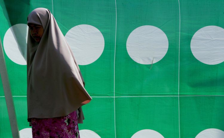 Fotografía de archivo de una mujer andando frente a un cartel electoral en Kuala Terengganu, la capital de la provincia de Terengganu, en el norte de Malasia. EFE/Shamshahrin Shamsudin