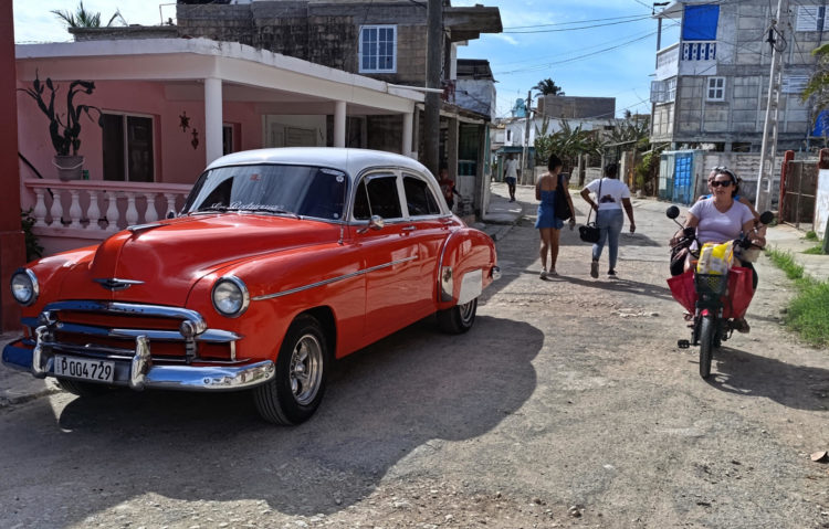 Personas pasan junto a un auto clásico este sábado en una calle de La Habana (Cuba). 2024 no fue un buen año para Cuba. EFE/ Ernesto Mastrascusa