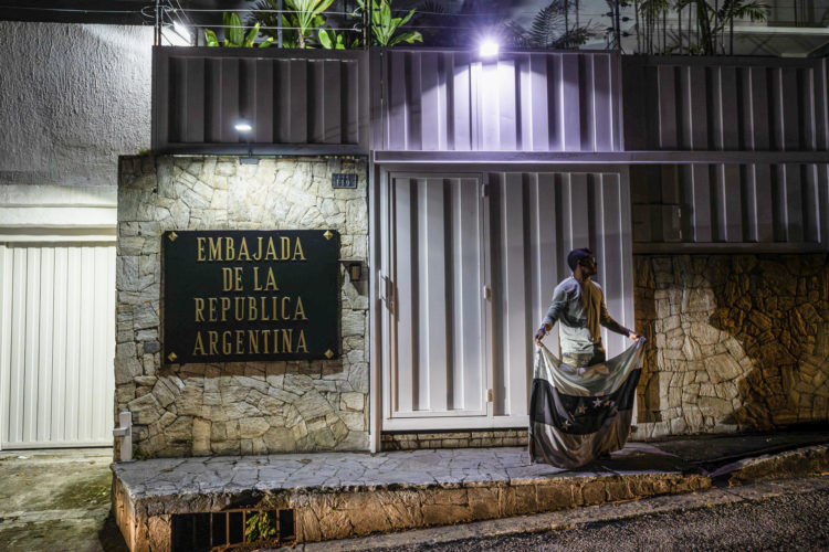 Fotografía de archivo de una persona que sostiene la bandera de Venezuela en color negro frente a la embajada de Argentina este lunes, en Caracas (Venezuela). EFE/ Henry Chirinos