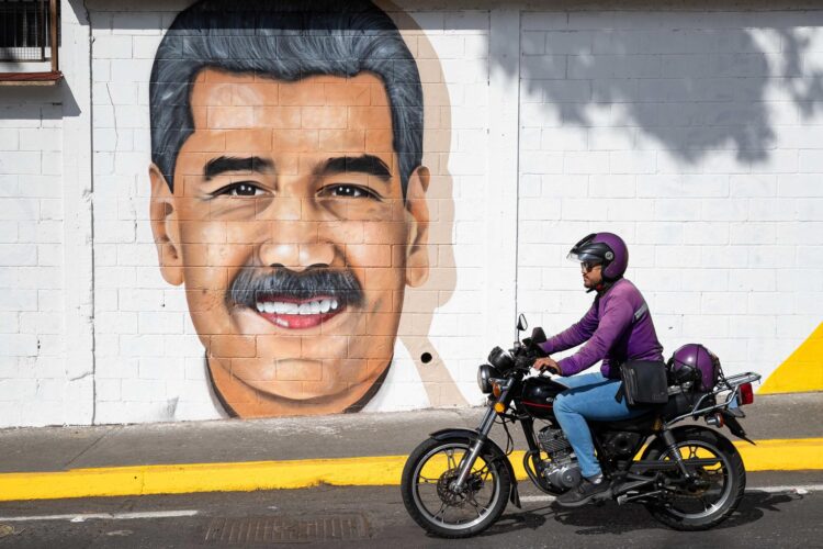 Un motociclista pasa frente a un mural del líder chavista Nicolás Maduro este martes, en Caracas (Venezuela). EFE/ Ronald Peña R.