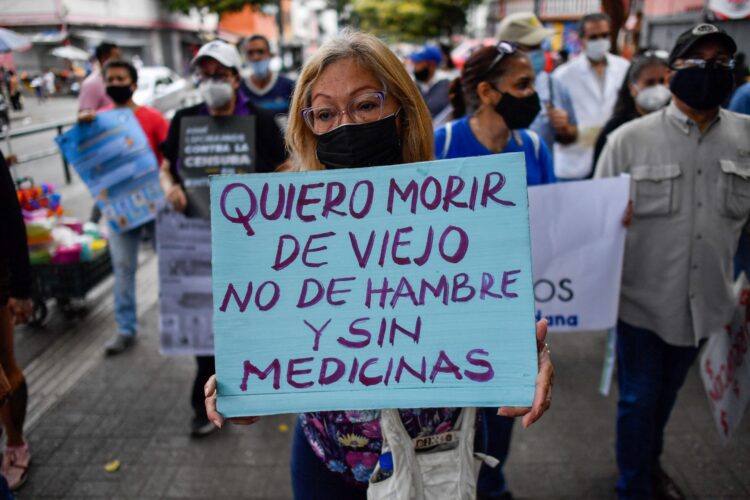 Un manifestante de la oposición sostiene un cartel que dice "Quiero morir de viejo, no de hambre y sin medicinas" durante una protesta contra la falta de electricidad, medicinas, agua, las malas condiciones de los hospitales y en demanda de salarios más justos, en Caracas el 14 de abril de 2022. Foto: Federico PARRA/AFP