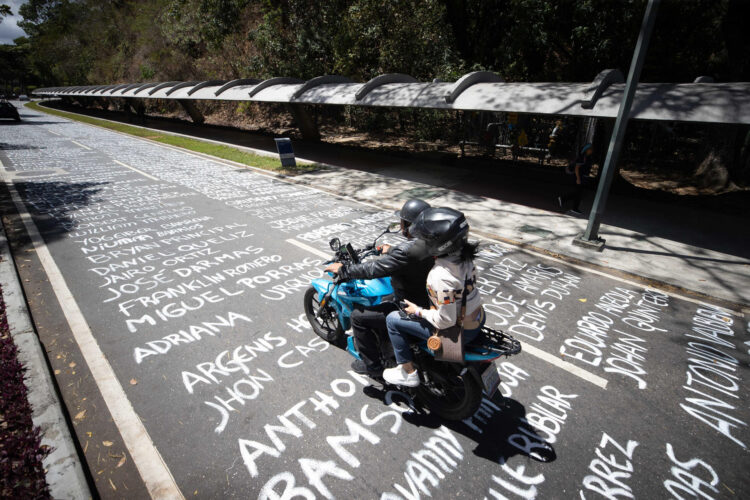 Dos personas en una motocicleta pasa por una calle pintada con los nombres de los manifestantes fallecidos desde el año 2014, este miércoles en Caracas (Venezuela). EFE/ Ronald Pena R