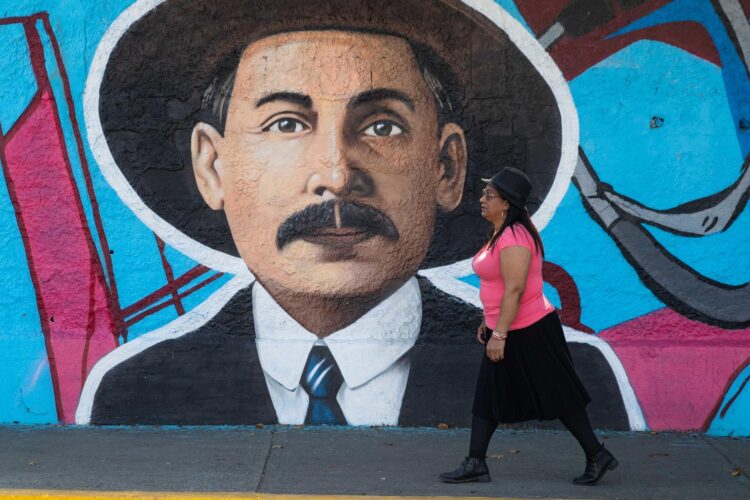 Una mujer camina frente a un mural del beato José Gregorio Hernández este martes, en Caracas (Venezuela). EFE/ Ronald Peña R.