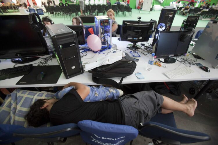 Un joven duerme en una sala llena de ordenadores, en una imagen de archivo. EFE/Sebastião Moreira