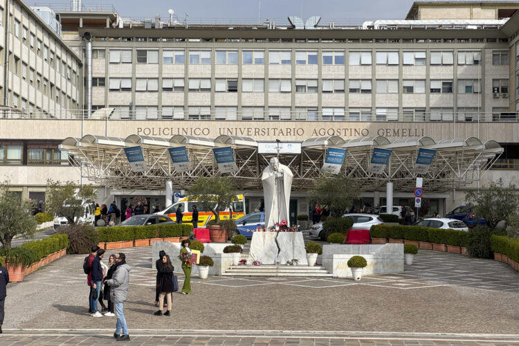 Velas y flores a los pies de la escultura de Juan Pablo II a las puertas del Hospital Gemelli de Roma donde permanece ingresado el papa Francisco, este miércoles. EFE/Daniel Cáceres