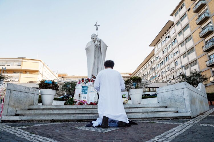 Una persona reza cerca de la estatua de Juan Pablo II frente al Hospital Agostino Gemelli, donde el Papa Francisco continúa su tratamiento por neumonía bilateral, en Roma, Italia, 06 de marzo de 2025. El papa fue admitido en el hospital el 14 de febrero debido a una infección del tracto respiratorio. (Papa, Italia, Roma) EFE/EPA/GIUSEPPE LAMI