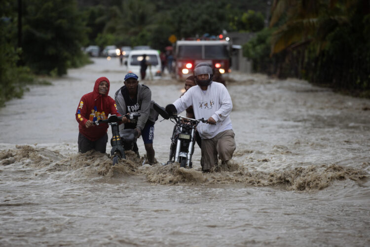 Fotografía de archivo de un grupo de personas al cruzar con dificultad una carretera inundada, producto de las intensas lluvias, en San José de Ocoa (República Dominicana). EFE/Orlando Barría