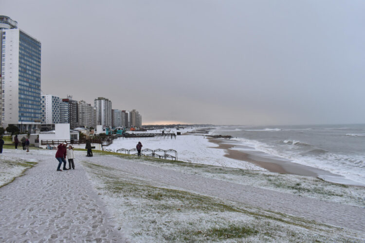 Personas caminan en una playa cubierta de nieve este lunes, en Miramar (Argentina). EFE/ Municipalidad de General Alvarado /