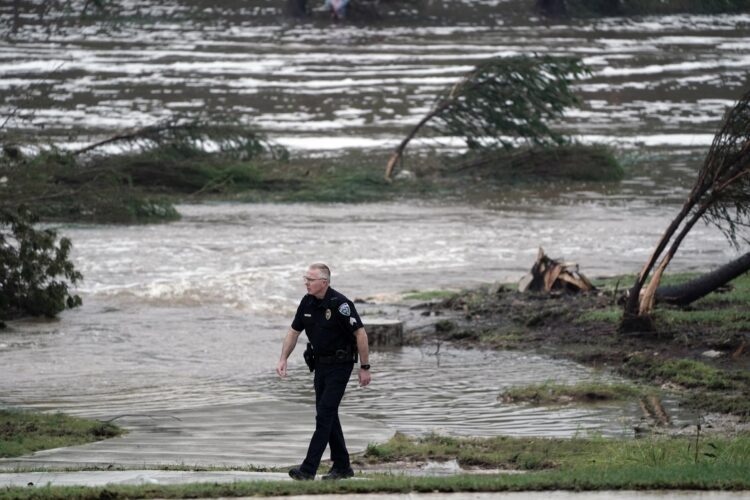 Un oficial de policía fue captado este sábado, 5 de julio, al caminar junto al terreno inundado por el desbordamiento del río Guadalupe, en Kerrville (Texas, EE.UU.). EFE/Dustin Safranek