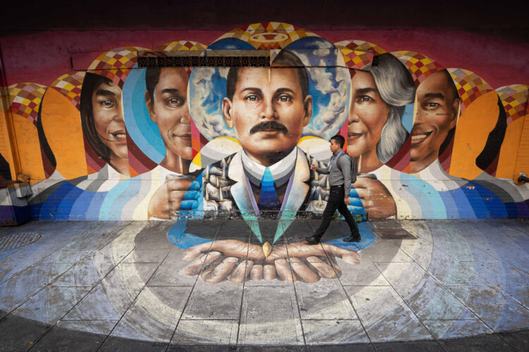 Fotografía del 15 de octubre del 2025 donde se observa a una persona caminando frente a un mural del médico José Gregorio Hernández, en Caracas (Venezuela). EFE/ Ronald Peña R