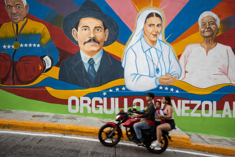 Fotografía del 15 de octubre de 2025 donde se observa personas transitando frente a un mural del médico José Gregorio Hernández, en Caracas (Venezuela). EFE/ Ronald Peña R
