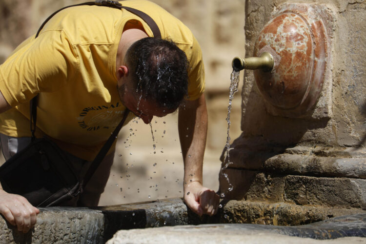 Un hombre se refresca con agua de una fuente de Córdoba, en una fotografía de archivo. EFE/Salas