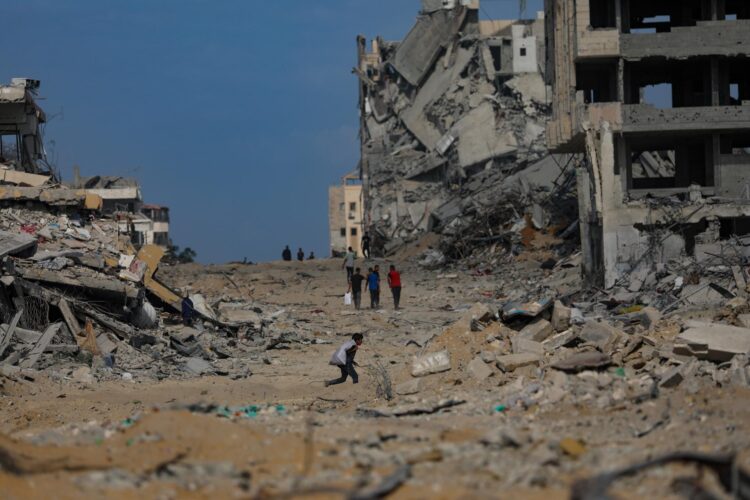 Palestinos caminan por una calle destruída por los bombardeos israelíes en Gaza. EFE/EPA/MOHAMMED SABER