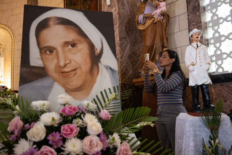 AME9764. CARACAS (VENEZUELA), 19/10/2025.- Una mujer toma una fotografía a una imagen de Santa Carmen Rendiles durante una misa en su honor este domingo, en Caracas (Venezuela). La Iglesia católica venezolana considera que sus primeros dos santos, el médico José Gregorio Hernández y la religiosa Carmen Rendiles, canonizados este domingo en el Vaticano, son motivo de esperanza para el futuro del país. EFE/ Ronald Peña R