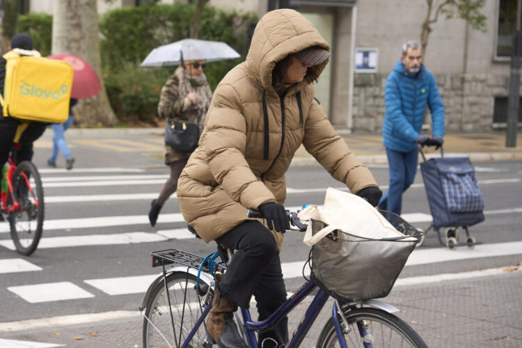 Una mujer circula en bicicleta y muy abrigada este miércoles en Vitoria. EFE/ L. Rico