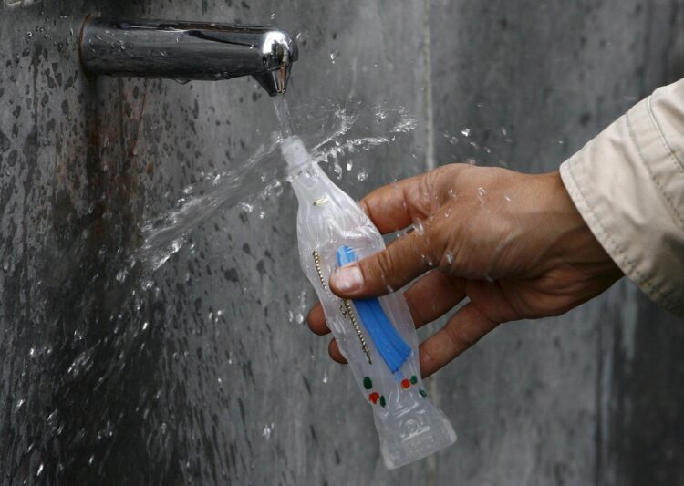 En la imagen de archivo, un peregrino llena de agua una botella con la forma de la Virgen María en una fuente de la gruta del santuario de Lourdes, Francia. EFE/Guillaume Horcajuelo