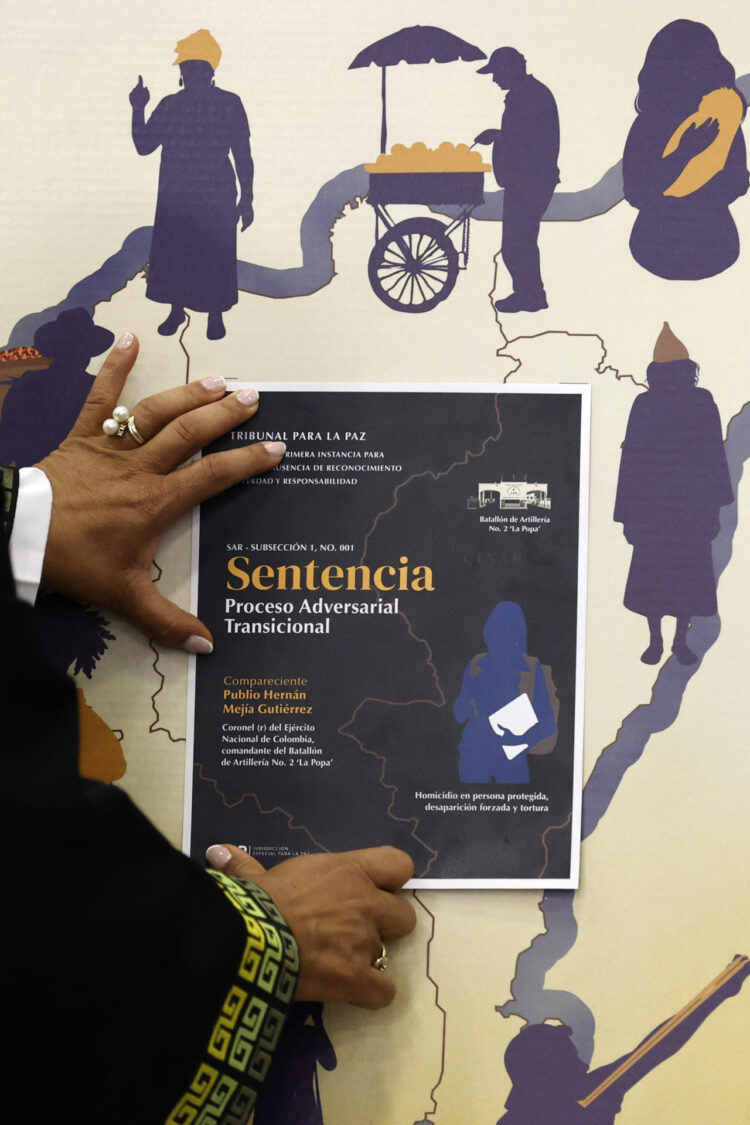 La magistrada de la sección de ausencia de reconocimiento de verdad y responsabilidad de la JEP, Reinere Jaramillo Chaverra, ubica la imagen de la sentencia en un mapa donde ocurrieron los hechos violentos durante el anuncio de la Primera Sentencia Adversarial Transicional en el proceso del coronel (r) Publio Hernán Mejía Gutiérrez, este viernes en Bogotá (Colombia). EFE/ Mauricio Dueñas Castañeda