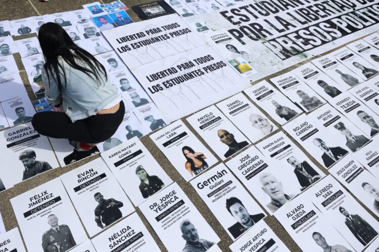 Una persona organiza carteles con imágenes de presos políticos este martes, en la Plaza del Rectorado UCV, en Caracas (Venezuela). EFE/ Miguel Gutiérrez