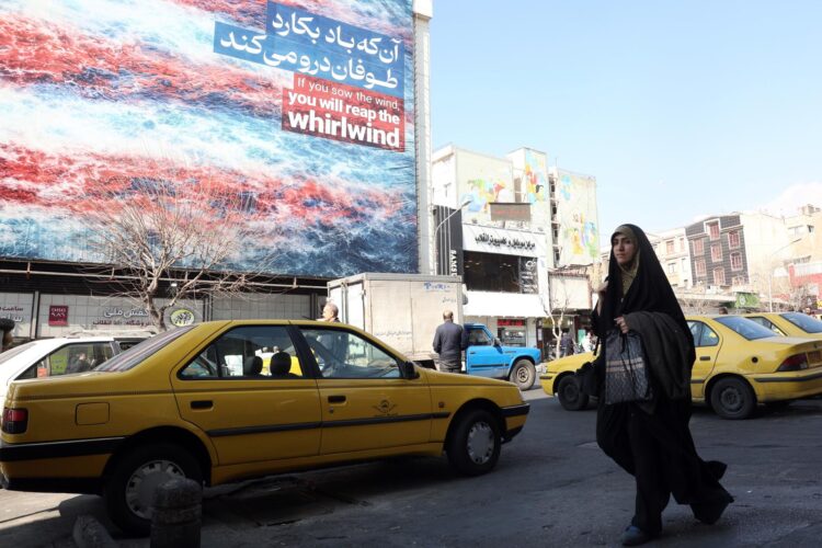 Una mujer iraní pasa frente a un cartel antiestadounidense en Teherán, Irán, el 25 de febrero de 2026. Irán y Estados Unidos mantienen este jueves una tercera ronda de negociaciones en Ginebra en busca de un acuerdo nuclear en medio de las amenazas de una intervención armada del presidente estadounidense, Donald Trump, quien ha realizado el mayor despliegue militar en Oriente Medio desde la guerra de Irak. EFE/EPA/ABEDIN TAHERKENAREH