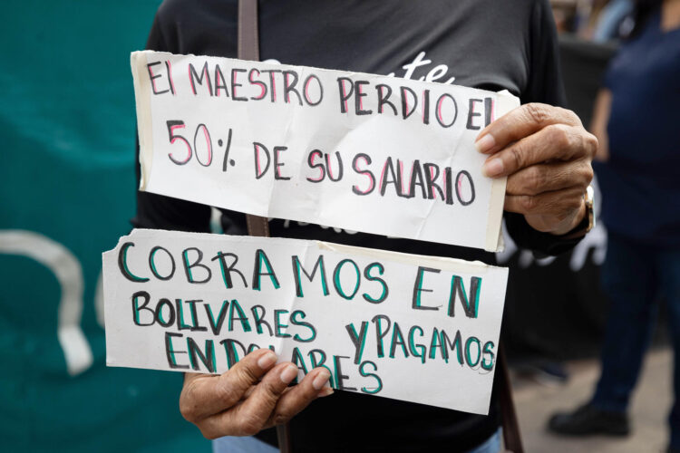 Una persona sostiene carteles durante una protesta para exigir un aumento de salarios y pensiones, congelados desde 2022 en 130 bolívares, unos 31 centavos de dólar al mes en la actualidad, este jueves frente al Ministerio del Trabajo en Caracas (Venezuela). EFE/ Ronald Peña R