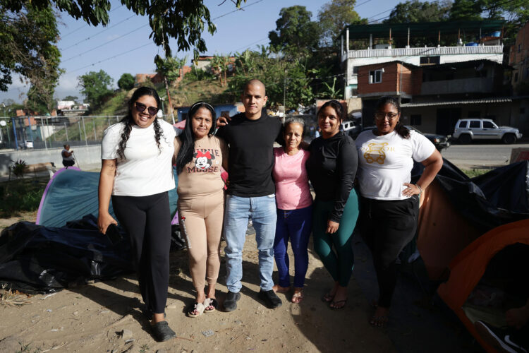José Espinoza (c), joven excarcelado, posa con familiares en un campamento este martes frente al centro penitenciario El Rodeo I, en Guatire, municipio Zamora (Venezuela). EFE/ Ronald Peña R.