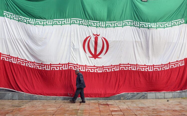 Un hombre pasa delante de una enorme bandera iraní, en una imagen de archivo. EFE/EPA/ABEDIN TAHERKENAREH