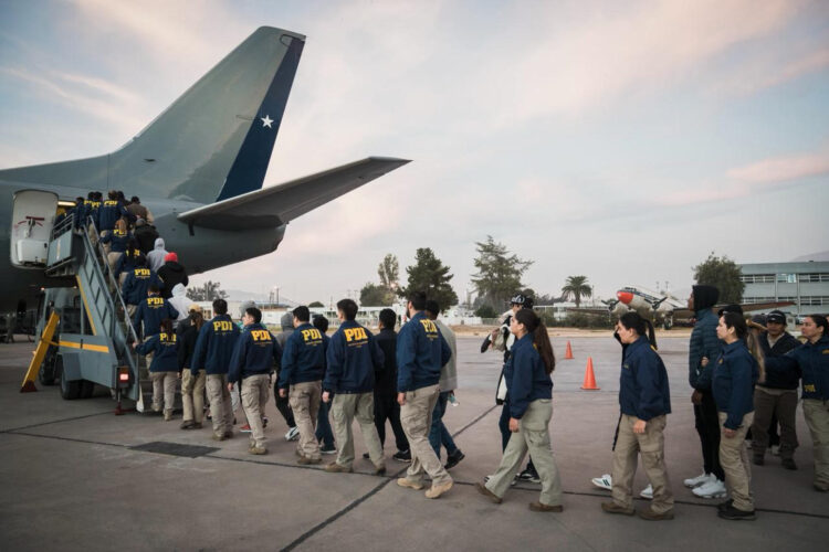 Fotografía cedida por el Ministerio del Interior de Chile que muestra a integrantes de la Policía de Investigaciones (PDI) trasladando a personas extranjeras deportados este jueves, en el Grupo de aviación Nº10 de la Fuerza Aérea de Chile, en Santiago (Chile).EFE/ Ministerio del Interior de Chile