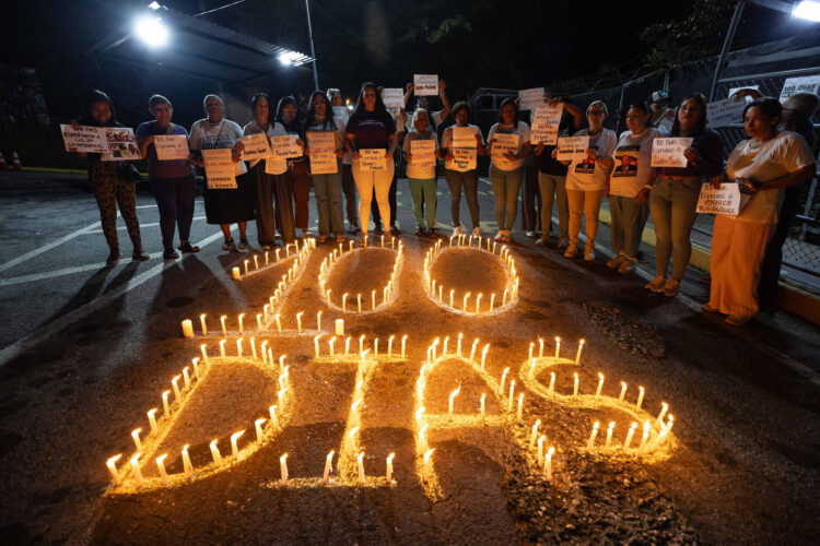 Personas sostienen carteles durante una vigilia afuera de la cárcel El Rodeo I este sábado, en Guatire (Venezuela). EFE/ Ronald Peña R