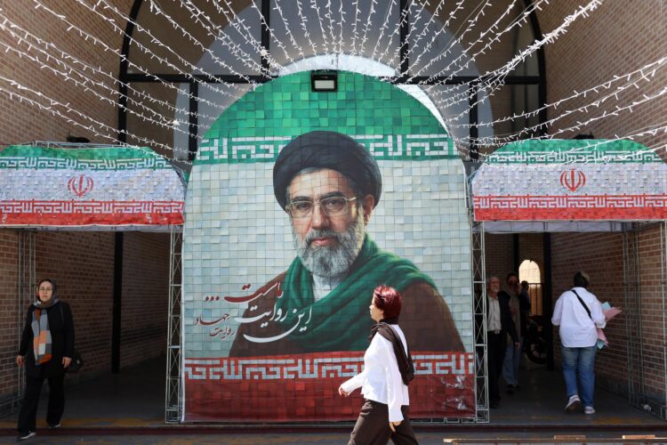 Iraníes caminan junto a una imagen del líder supremo de Irán, el ayatolá Mojtaba Jamenei, en una calle de Teherán, Irán, el pasado 6 de mayo de 2026. El presidente de EE.UU., Donald Trump, anunció la pausa de la operación de escolta de buques a través del Estrecho de Ormuz, insinuando avances en las conversaciones de paz con Teherán. (Teherán) EFE/EPA/ABEDIN TAHERKENAREH