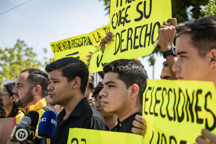 Jóvenes del partido opositor Primero Justicia (PJ) sostienen carteles durante una protesta frente a las oficinas del Concejo Nacional Electoral (CNE), en Maracaibo (Venezuela). EFE/ Henry Chirinos