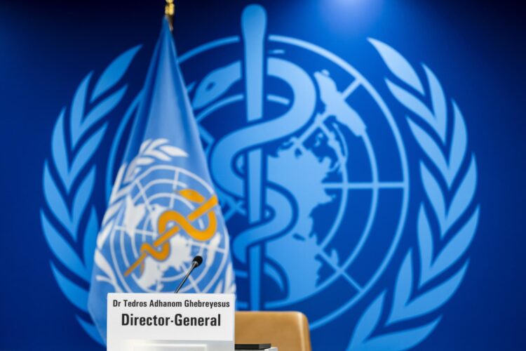 Fotografía de archivo de la placa de identificación de Tedros Adhanom Ghebreyesus, director general de la Organización Mundial de la Salud (OMS), frente a la bandera y el logotipo de la OMS, en la sede de la organización en Ginebra, Suiza. EFE/EPA/MARTIAL TREZZINI