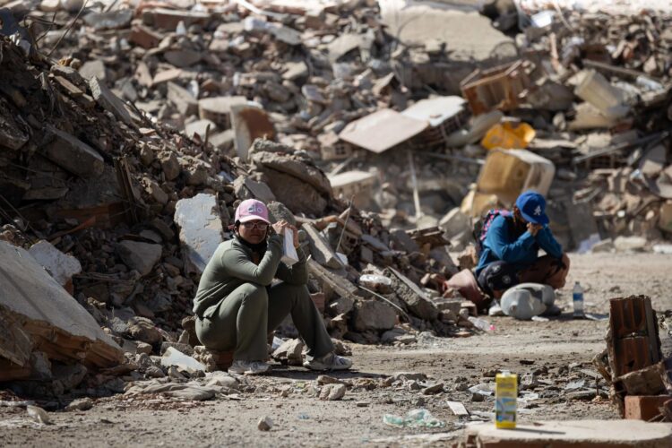 Personas esperan este lunes junto a los escombros de un edificio afectado por los terremotos en La Guaira (Venezuela). EFE/ Ronald Peña R