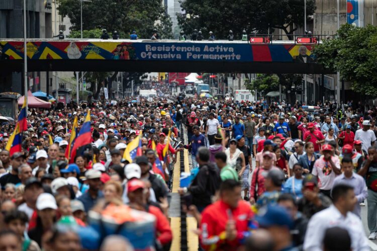 Personas marchan hacia la sede del Parlamento para entregar un documento en el que manifestaron su respaldo al proceso de diálogo entre un sector de la oposición y el Gobierno, y para exigir el levantamiento de sanciones contra Venezuela, este martes en Caracas (Venezuela). EFE/ Ronald Peña R