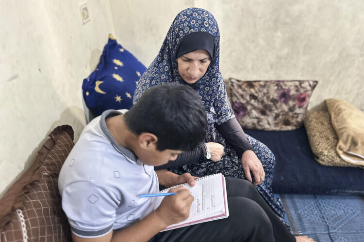 AL MAWASI (FRANJA DE GAZA), 06/10/2026.- Walá Awad realiza tareas con su hijo en Al Mawasi (Franja de Gaza), donde la terapeuta Nawal Asqul (terapeuta) atiende a niños afectados por el trauma de la guerra. Tres años después de la ofensiva israelí en Gaza, los niños gazatíes afrontan graves secuelas psicológicas: pesadillas, incontinencia, tartamudez, agresividad e hiperactividad son algunos de los síntomas detectados por terapeutas, mientras miles de menores han perdido a uno o ambos progenitores. EFE/